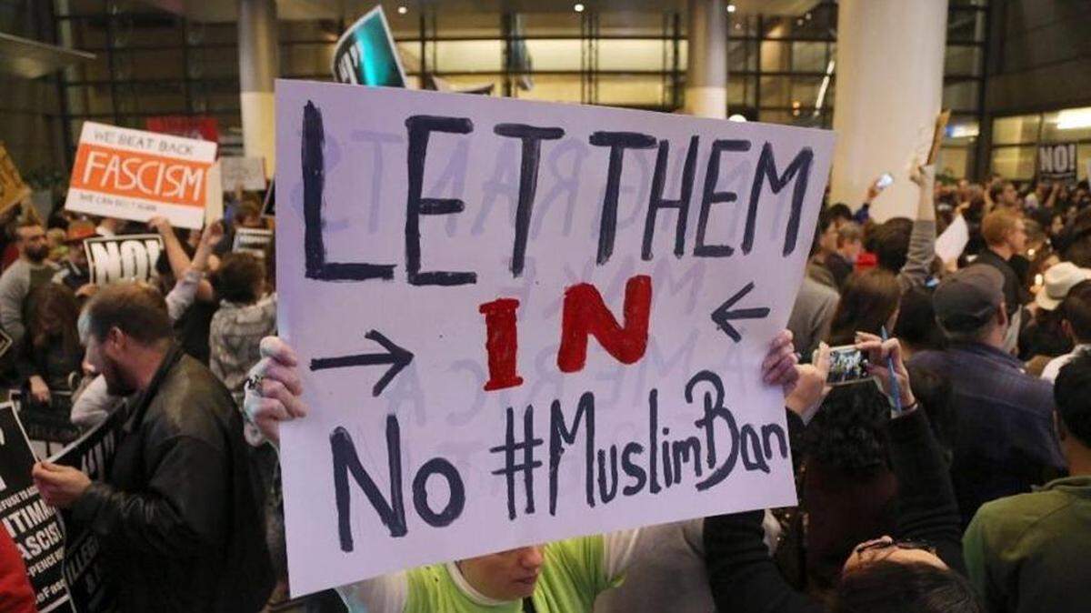 Protesters at John F. Kennedy International Airport in New York rally Saturday after two Iraqi refugees were detained while trying to enter the country.