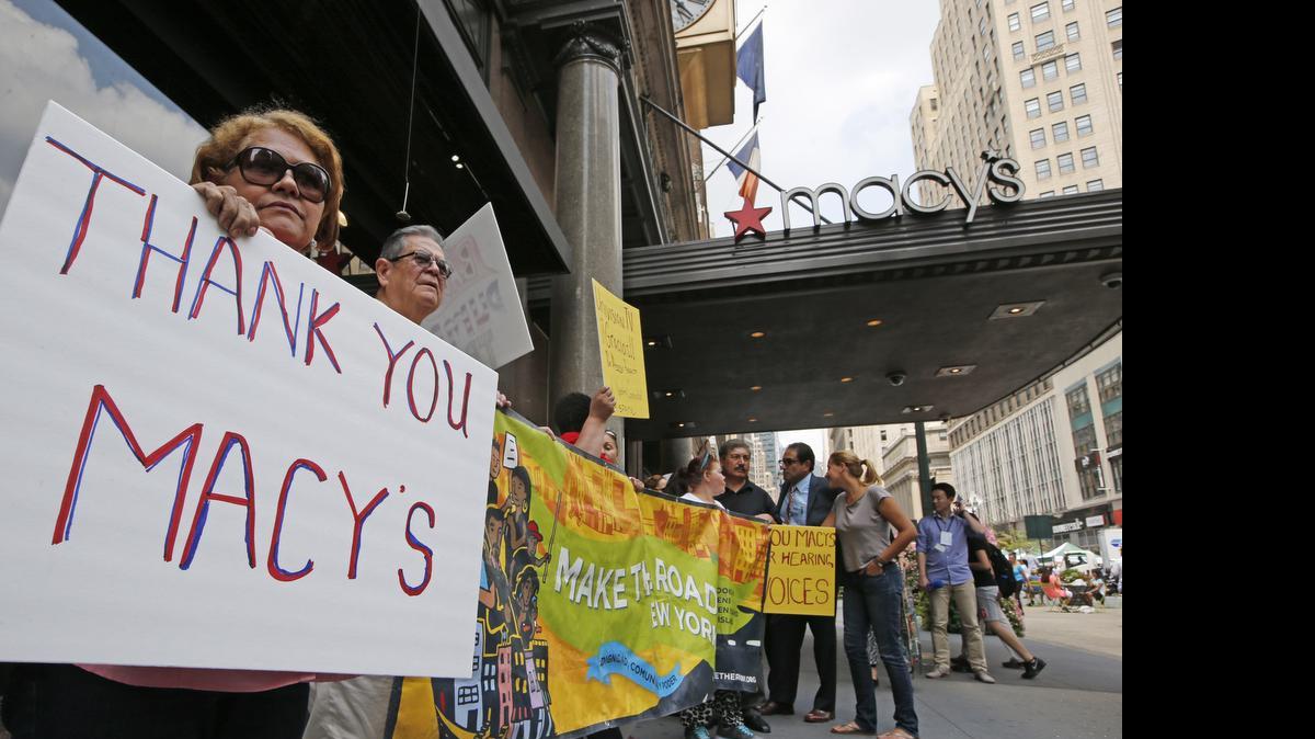 
ADIOS, TRUMP: People hold signs in front of Macy's Herald Square flagship store in New York after it severed ties with Donald Trump for his remarks about Mexican immigrants.
