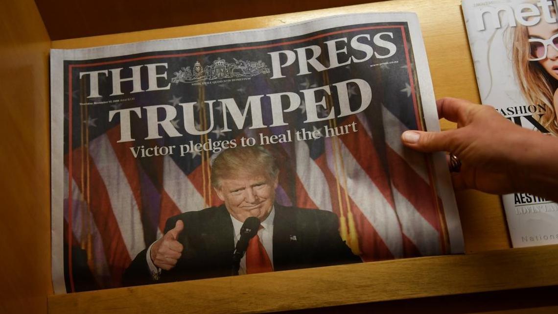 A woman reaches for a local newspaper reporting on the election victory of US President-elect Donald Trump in Christchurch, New Zealand, Thursday, Nov. 10, 2016.