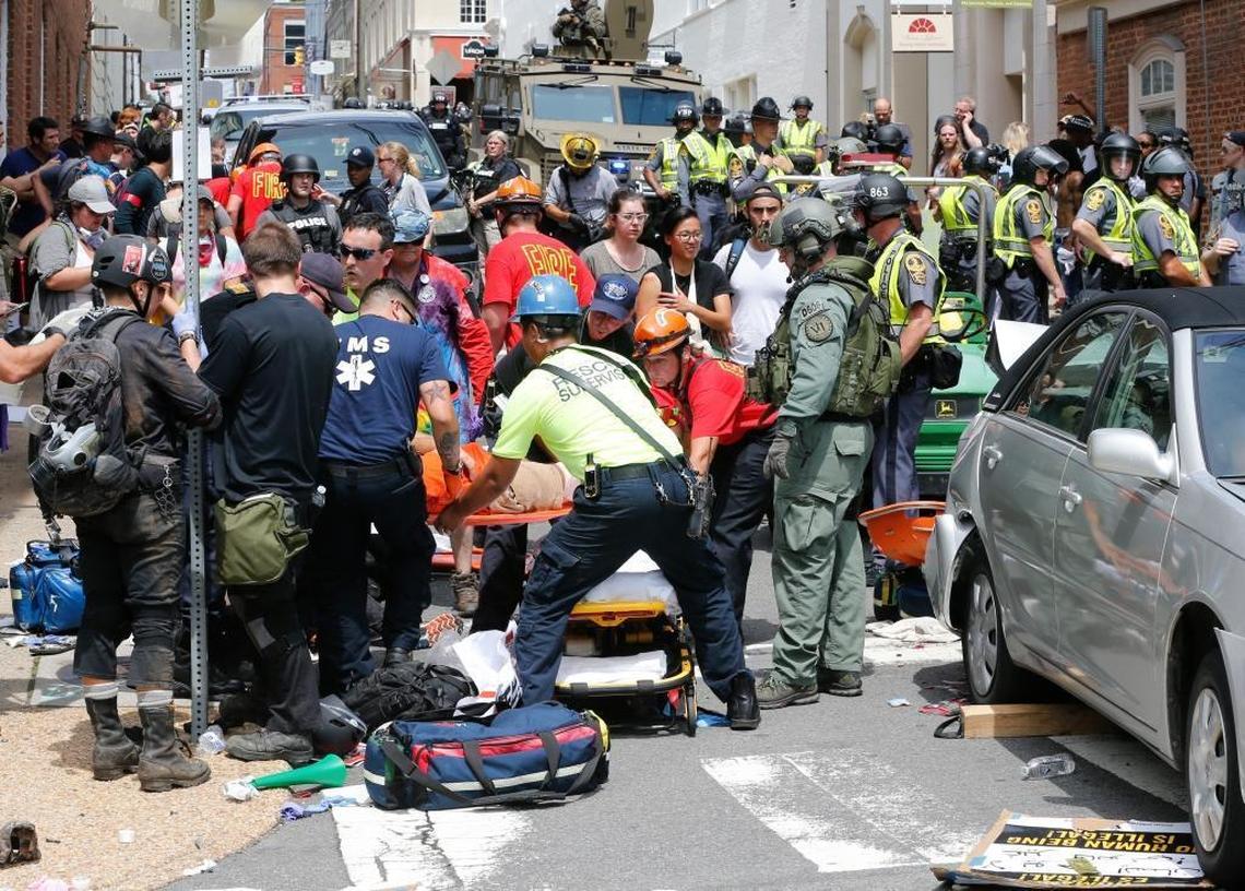 Rescue personnel help injured people after a car ran into a large group of protesters after an white nationalist rally in Charlottesville, Va., Saturday. The nationalists were holding the rally to protest plans by the city of Charlottesville to remove a statue of Confederate Gen. Robert E. Lee. There were several hundred protesters marching in a long line when the car drove into a group of them.