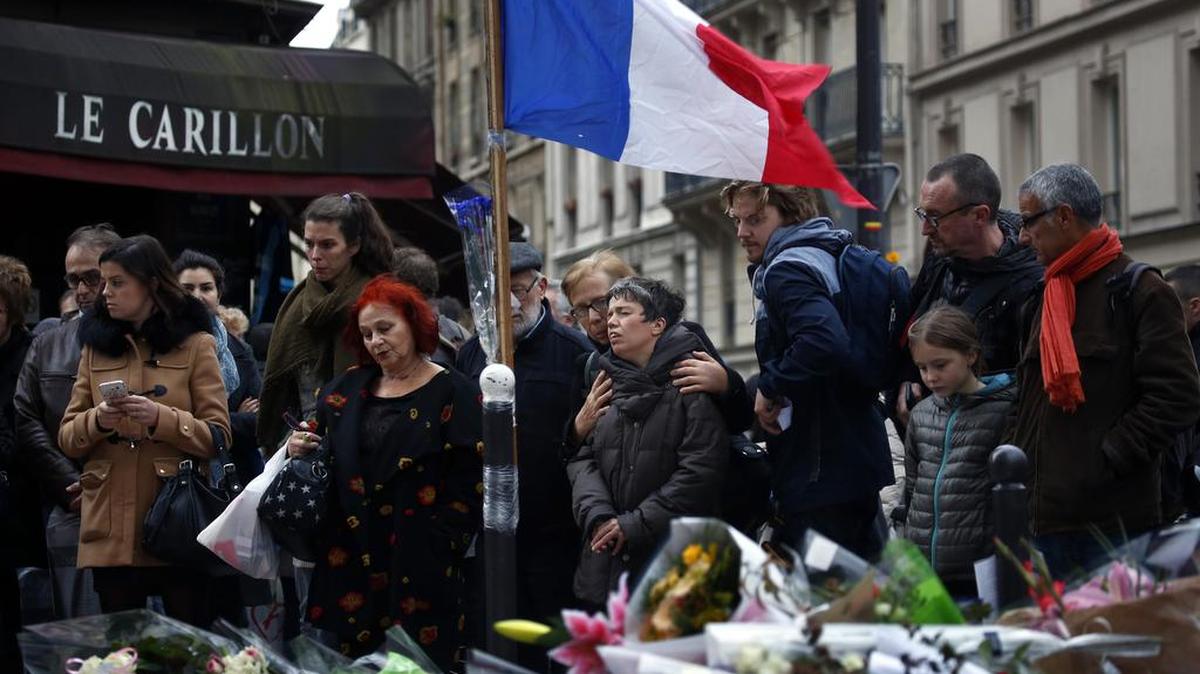 People gather in front of Le Carillon cafe, a site of the attacks in Paris. President François Hollande said victims were of 19 nationalities.