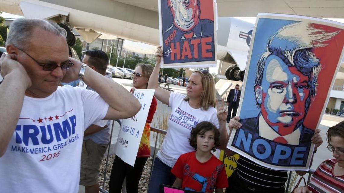 During the elections, a Donald Trump supporter, left, plugs his ears while passing protesters waving signs and chanting against the Republican presidential nominee at a Trump rally in Denver.