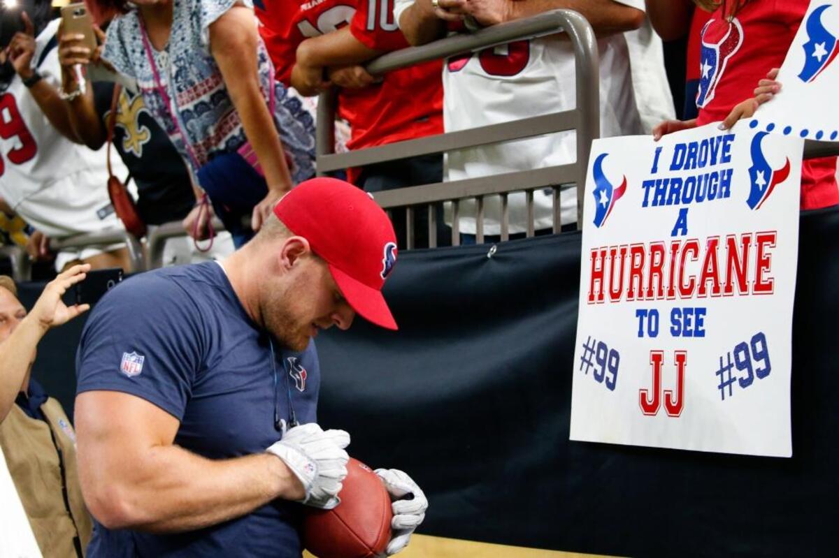 Houston Texans defensive end J.J. Watt signs autographs for fans holding sings referencing Hurricane Harvey before an NFL football game against the New Orleans Saints in New Orleans on Saturday night.