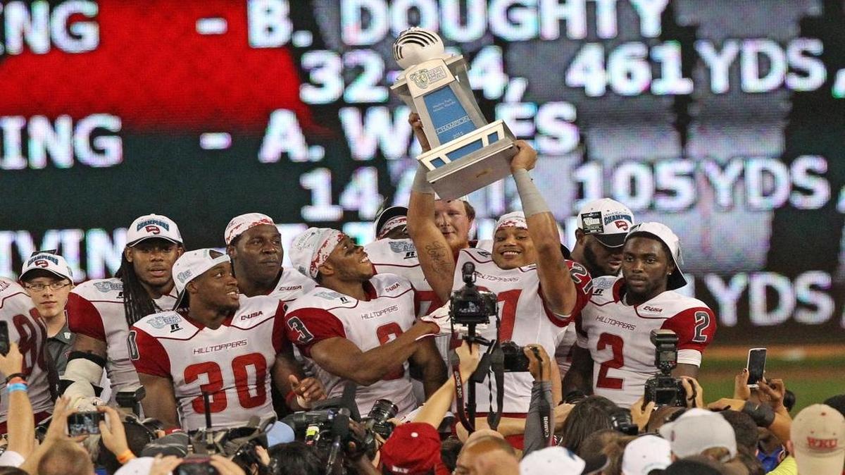 Western Kentucky’s Jared Dangerfield holds up the trophy after defeating the University of South Florida in the Miami Beach Bowl at Marlins Park in Miami on Monday, Dec. 21, 2015.
