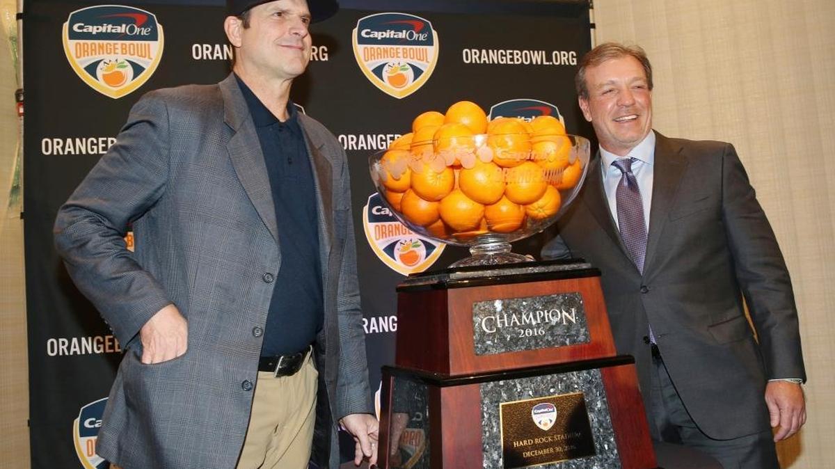 Michigan coach Jim Harbaugh and FSU’s Jimbo Fisher pose with the Orange Bowl trophy in Fort Lauderdale on Thursday morning.