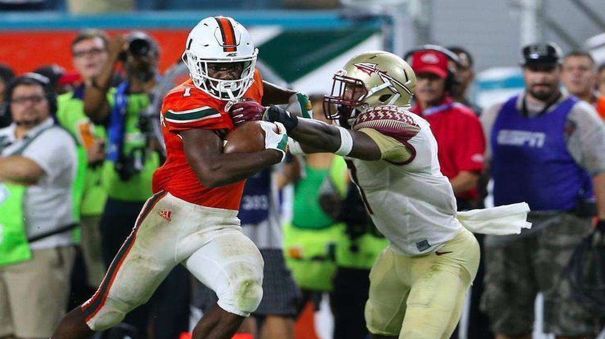 University of Miami running back Mark Walton runs against Florida State Seminoles defensive back Ermon Lane at Hard Rock Stadium on Saturday October 8, 2016, in Miami Gardens.