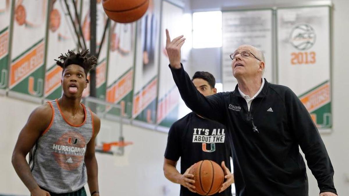 Miami head coach Jim Larranaga, right, tosses the ball as Lonnie Walker, left, looks on, Mon., Oct. 23, 2017, during an NCAA basketball media day practice, in Coral Gables, Fla.