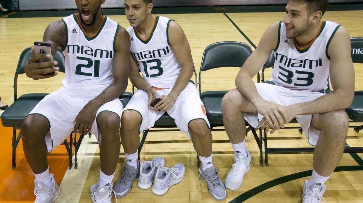 Kamari Murphy (21) and guard Angel Rodriguez (13) pose for their own photo as forward Ivan Cruz Uceda (33) looks on, while they wait to take a team photo during Miami's media day in Coral Gables, Fla.