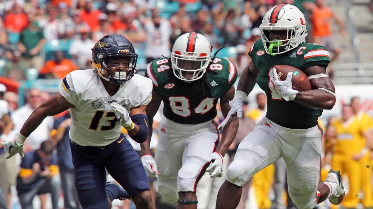 Miami Hurricanes Mark Walton (1) runs for a first quarter touchdown as Toledo Rockets Ka'dar Hollman (13) trails at Hard Rock Stadium in Miami Gardens, Florida, Sept. 23, 2017.