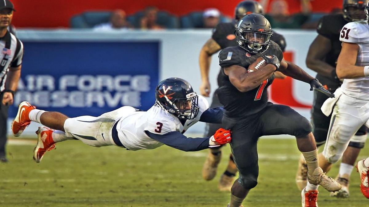 Miami Hurricanes Mark Walton breaks away from Virginia Cavaliers Quin Blanding in the third quarter at Sun Life Stadium in Miami Gardens, Florida, November 7, 2015.