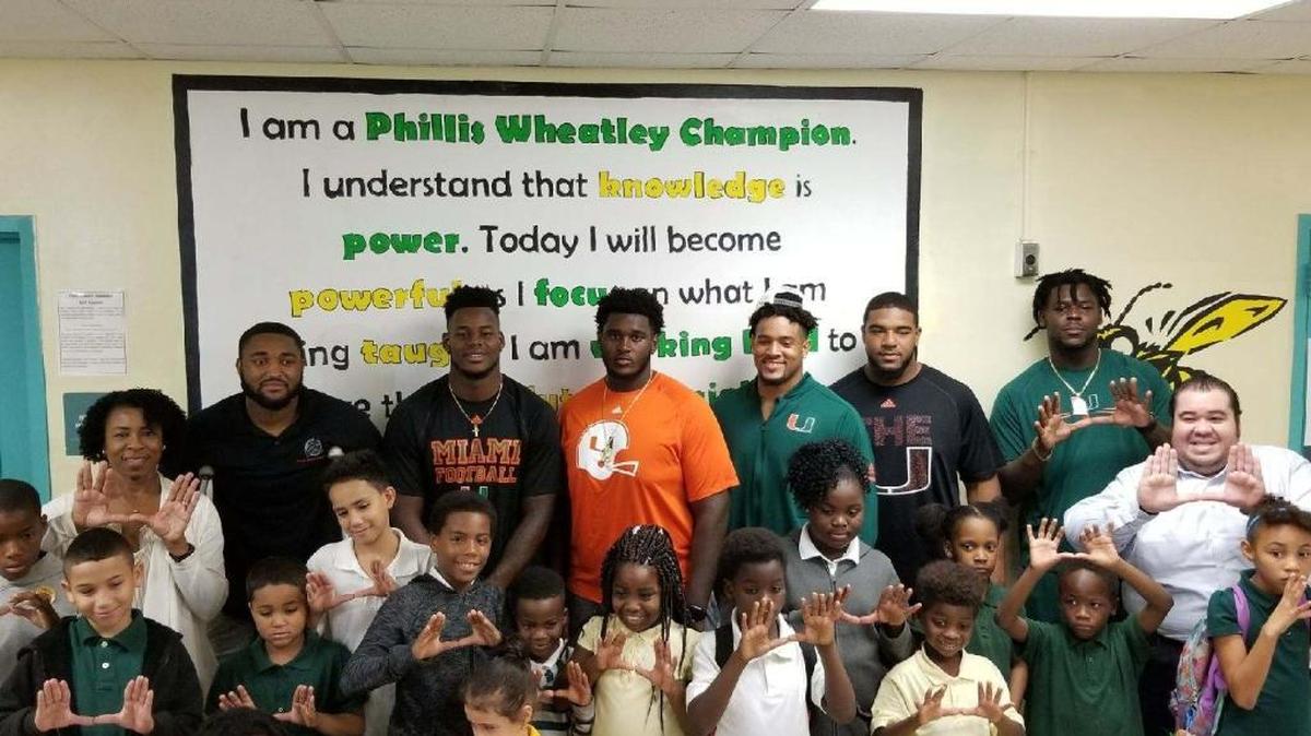 Several Miami Hurricanes, led by defensive end Demetrius Jackson, gave out turkeys and canned goods to some children and their families at Phillis Wheatley Elementary in Overtown, where Jackson attended. From left are principal Cathy Williams, Jackson, and teammates Christopher Herndon, Kendrick Norton, Trent Harris, Pat Bethel and Chad Thomas. Below Thomas is assistant principal Michael Lazo.