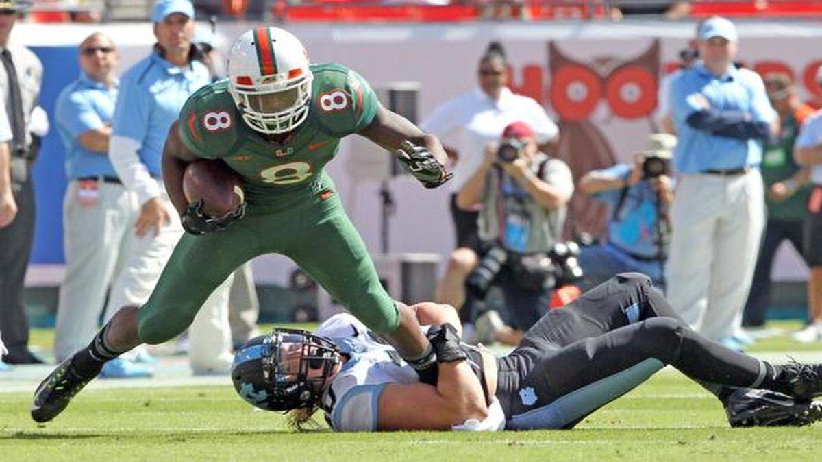 
Miami Hurricanes’ Duke Johnson scrambles for yards in the first quarter as North Carolina Tar Heels’ Jeff Schoettmer holds his leg at Sun Life Stadium in Miami Gardens, Florida, Novemebr 1, 2014.
