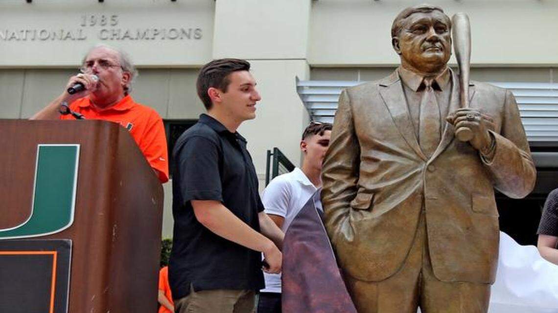 
Kyle and Amanda Gonzales, grandchildren of late UM baseball coach Ron Fraser, unveil the statue at a ceremony at Mark Light Field on April 24, 2015. Behind the podium is UM baseball announcer Jay Rokeach. 
