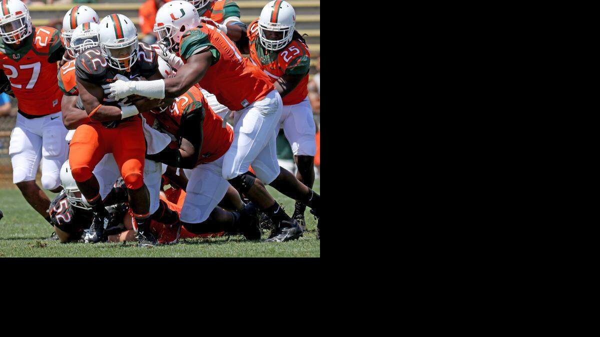 
springtime surge: Colin Alford tries to break free from a gang of Canes tacklers during the University of Miami spring game on Saturday at Lockhart Stadium.
