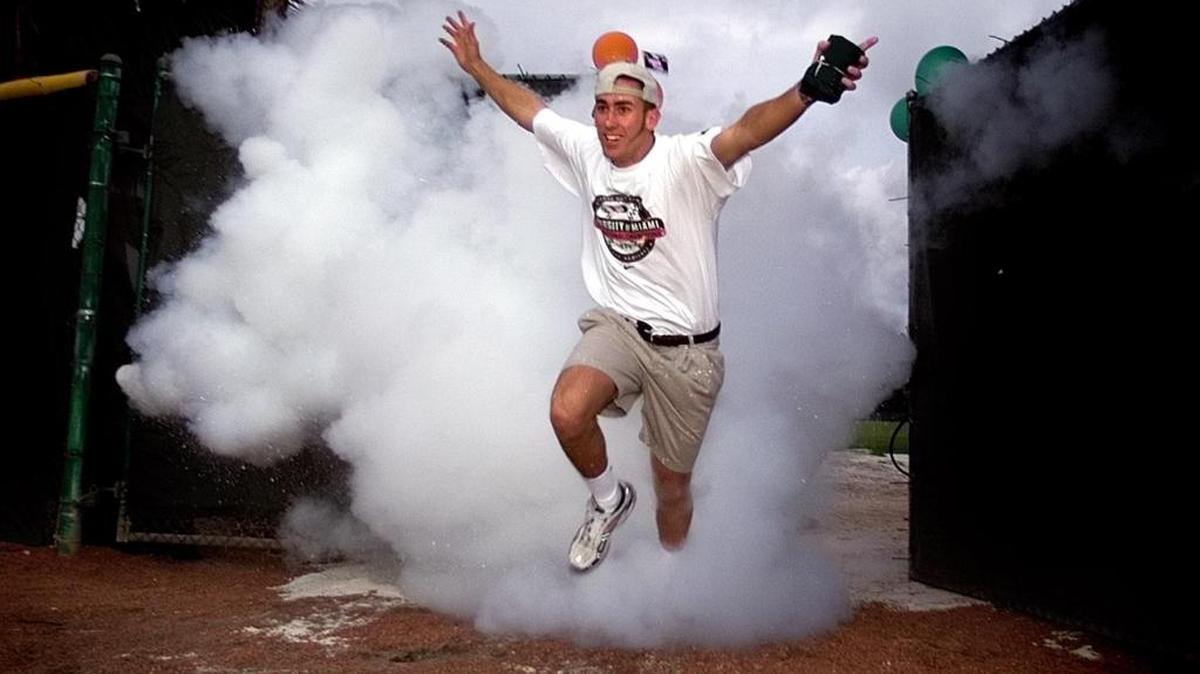 University of Miami catcher — and now current UCF coach — Greg Lovelady emerges from the smoke at Miami’s 1999 national championship ceremony at Mark Light Stadium.