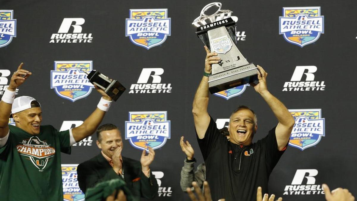 Miami Hurricanes head coach Mark Richt raises the championship trophy after the University of Miami defeats West Virginia at the Russell Athletic Bowl in Orlando Wednesday, December 28, 2016.