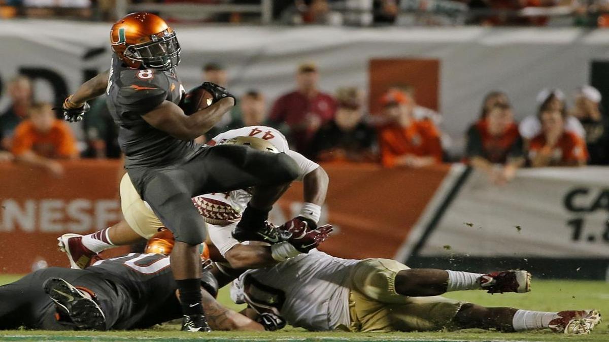 
Miami Hurricanes running back Duke Johnson (#8) gets tripped up by Florida State Seminoles defensive tackle Arthur Williams (#96, bottom) and Florida State Seminoles defensive end DeMarcus Walker (#44) at SunLife Stadium in Miami Gardens on Saturday, November 15, 2014.
