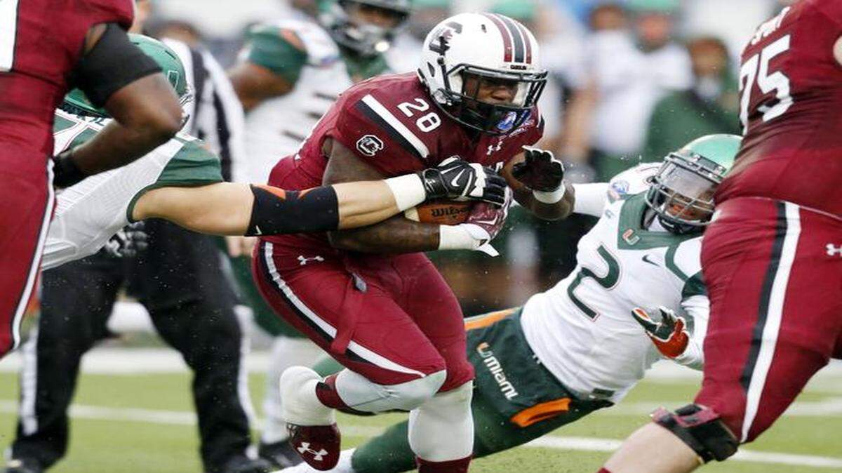 
South Carolina running back Mike Davis (28) runs through Miami defenders in the first half of the Independence Bowl NCAA college football game in Shreveport, La., Saturday, Dec. 27, 2014. 
