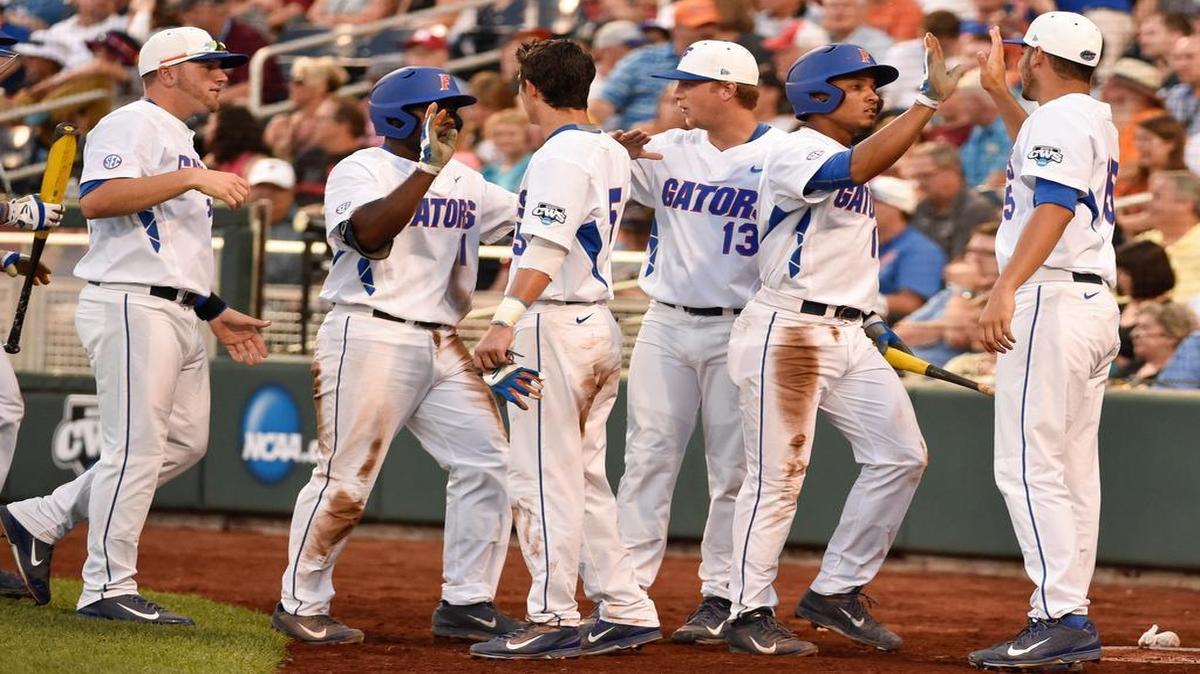 
Florida third baseman Josh Tobias, second from left, and Richie Martin, second from right, are greeted at the dugout after scoring on a two-run single byJJ Schwarz during the fourth inning of an NCAA College World Series baseball game against Miami at TD Ameritrade Park in Omaha, Neb., Saturday, June 13, 2015. Florida scored 11 runs in the fourth inning. 
