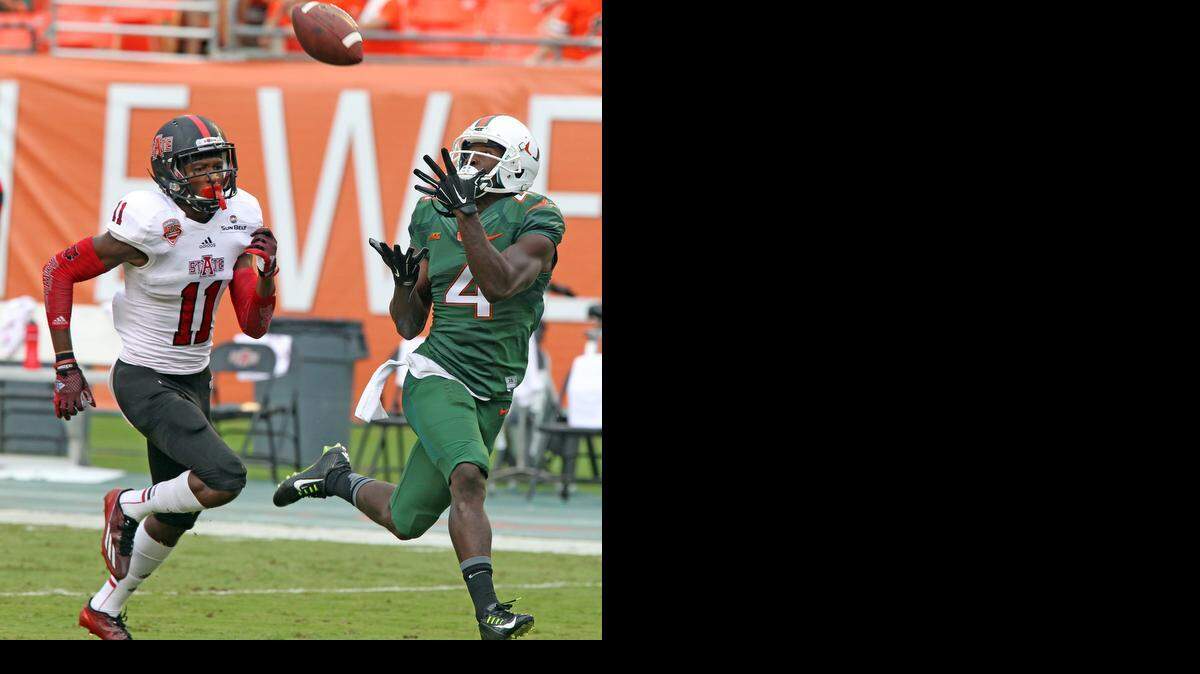 
University of Miami wide receiver Philip Dorsett catches the ball and scores a first quarter touchdown as Arkansas State's Sterling Young fails to defend at Sun Life Stadium in Miami Gardens on Sept. 13, 2014.
