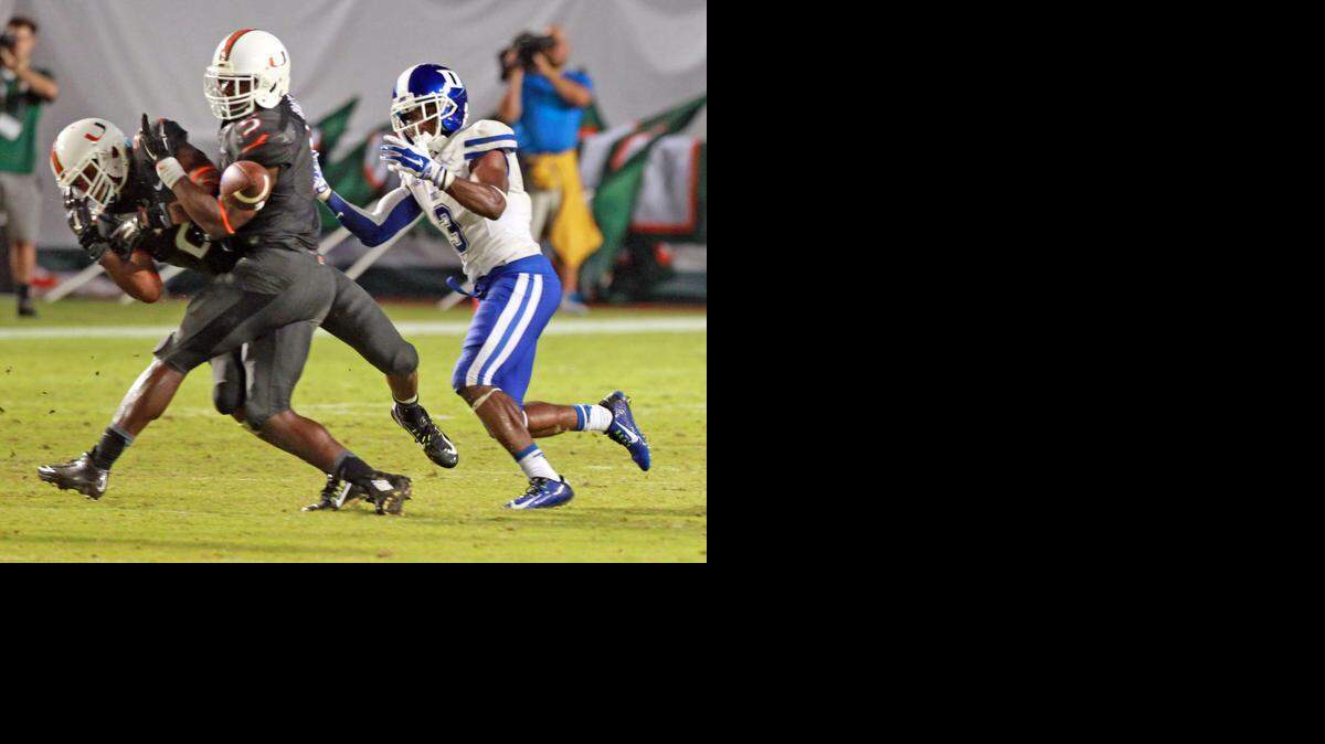 Miami Hurricanes' Deon Bush and Jermaine Grace try to intercept the ball but drop it late in the fourth quarter as they defeat Duke at Sun Life Stadium in Miami Gardens, Fla., September 27, 2014.
