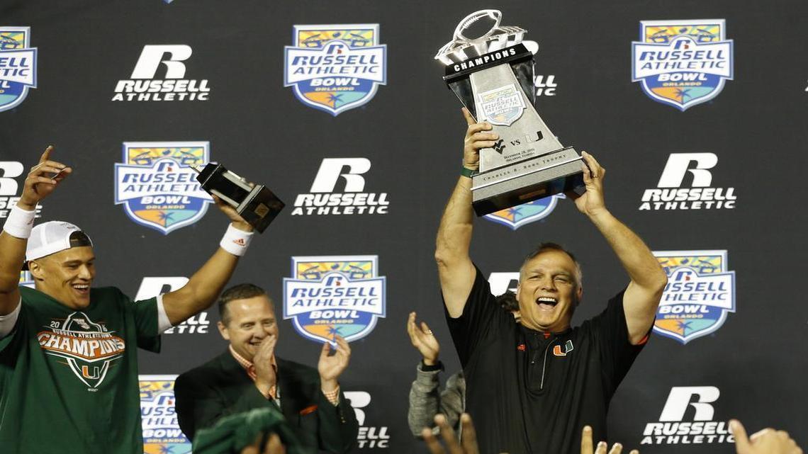 Miami Hurricanes coach Mark Richt is shown raising the Russell Athletic Bowl championship trophy after the Canes defeated West Virginia in Orlando in 2016. The Hurricanes are set to square in the Pinstripe Bowl at Yankee Stadium against the Wisconsin Badgers at 5:15 p.m. on Dec. 27 in a rematch of the Orange Bowl last year.