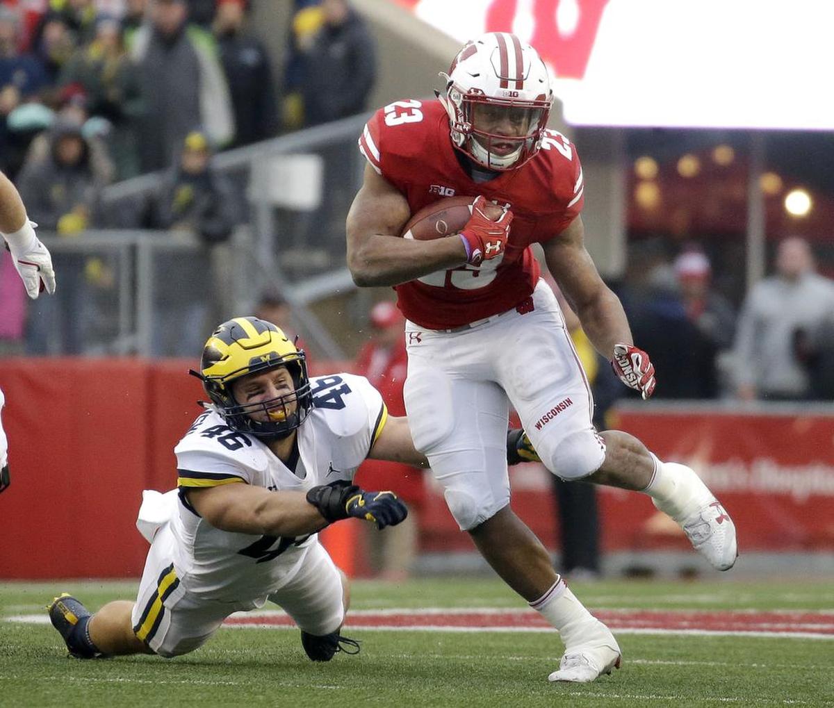 Wisconsin’s Jonathan Taylor runs past Michigan’s Chris Hanlon on Nov. 18, 2017, in Madison, Wisconsin. Taylor will face the Miami Hurricanes on Dec. 27, 2018, in the Pinstripe Bowl at Yankee Stadium.