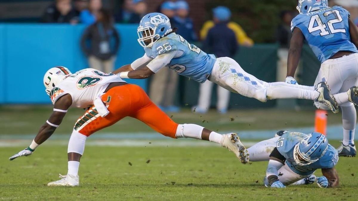 North Carolina's Dominiquie Green (26) dives over teammate Donnie Miles (15) to tackle Miami's David Njoku after a pass reception during the first half of an NCAA college football game, in Chapel Hill, N.C., Saturday, Nov. 14, 2015.
