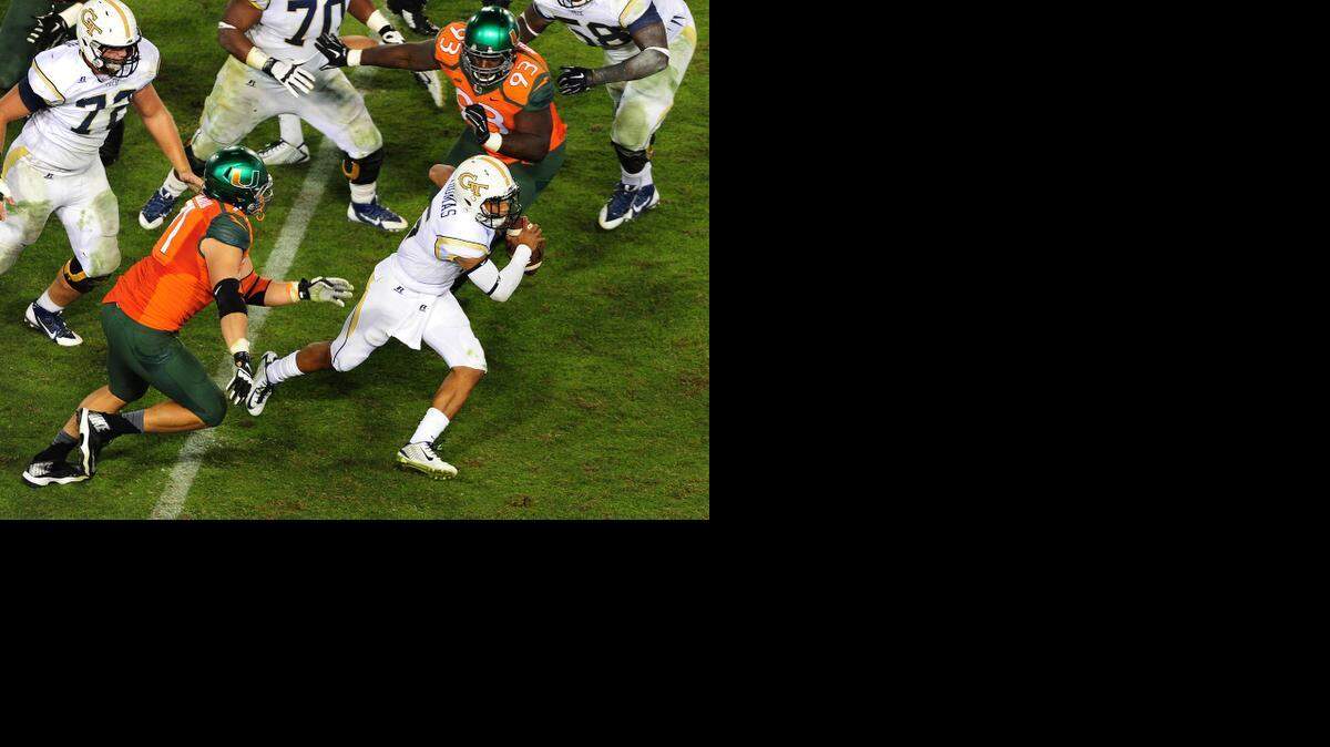 
 Justin Thomas #5 of the Georgia Tech Yellow Jackets scrambles away from Anthony Chickillo #71 and Calvin Heurtelou #93 of the Miami Hurricanes at Bobby Dodd Stadium on October 4, 2014 in Atlanta, Georgia. 
