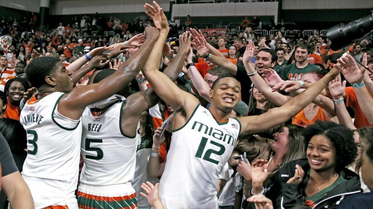 Miami Hurricanes players Anthony Lawrence Jr. (3), Davon Reed (5) and James Palmer (12) celebrate with fans after a 73-65 victory against Louisville at BankUnited Center in Coral Gables, Florida, on Saturday, February 27, 2016.
