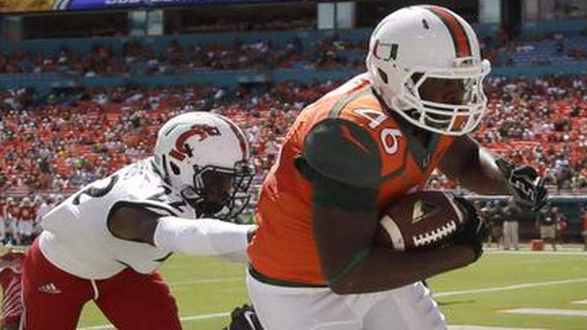 
UM tight end Clive Walford scores a touchdown as Cincinnati safety Zach Edwards defends Saturday, Oct. 11, 2014, in Miami Gardens, Fla.
