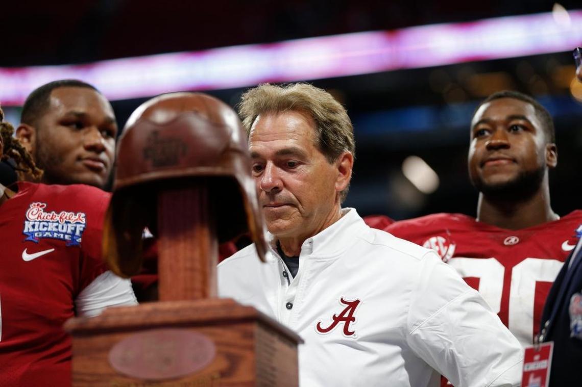 Alabama head coach Nick Saban stands on the podium with the Leather Helmet trophy after beating Florida State in Atlanta on Saturday night.