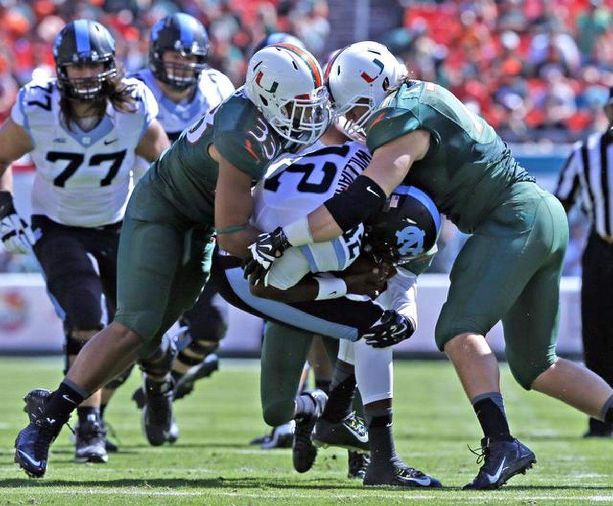 Miami Hurricanes’ Trent Harris and Anthony Chickillo (right) sack North Carolina Tar Heels quarterback Marquise Williams in the first quarter at Sun Life Stadium in Miami Gardens, Florida, November 1, 2014.