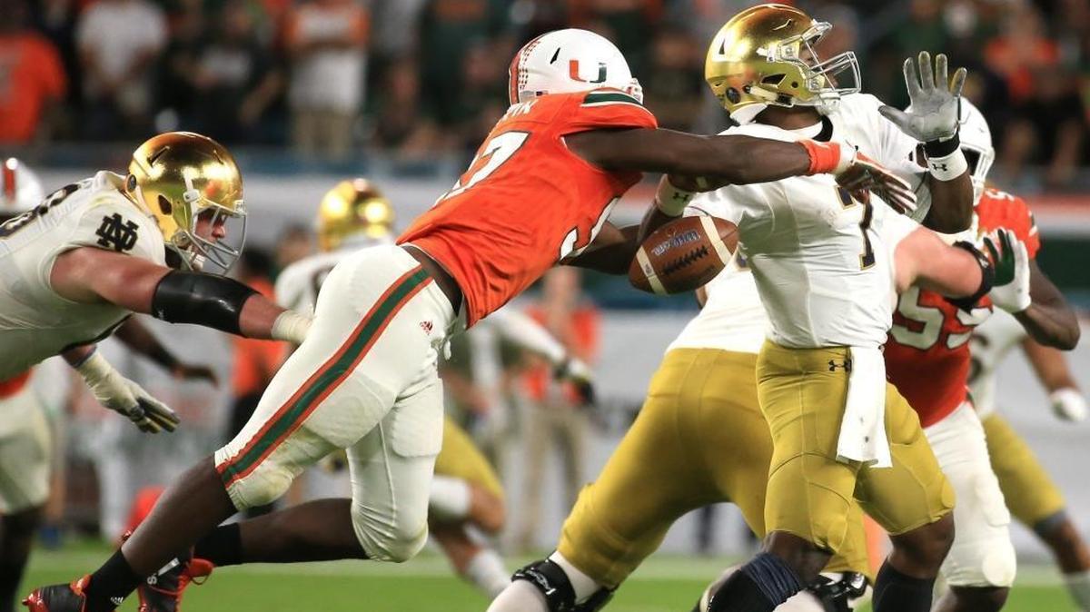 Miami Hurricanes defensive end Jonathan Garvin (97) knocks the ball out of the hands of Notre Dame Fighting Irish quarterback Brandon Wimbush (7) for a fumble in the fourth quarter against Notre Dame at Hard Rock Stadium on Saturday, Nov. 11, 2017.