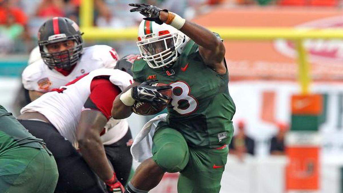
University of Miami's Duke Johnson leaps over teammate Alex Gall to score a first quarter touchdown aganist Arkansas State at Sun Life Stadium in Miami Gardens, Florida, Sept. 13, 2014.
