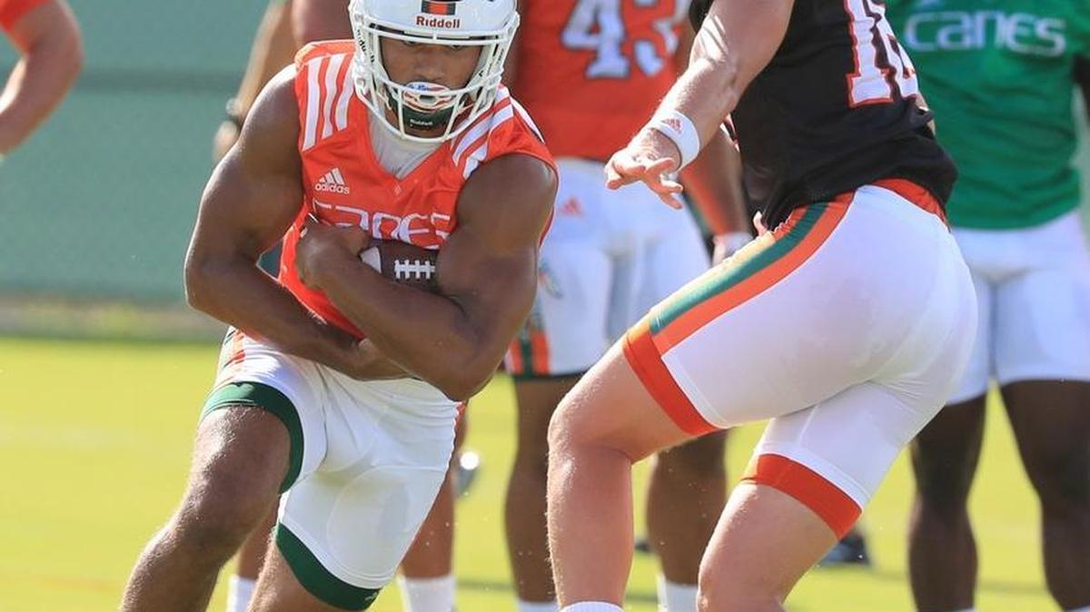 Travis Homer (24) takes a handoff from quarterback Evan Shirreffs (16) as University of Miami opens fall football camp at Greentree Field on Tues., Aug. 1, 2017.
