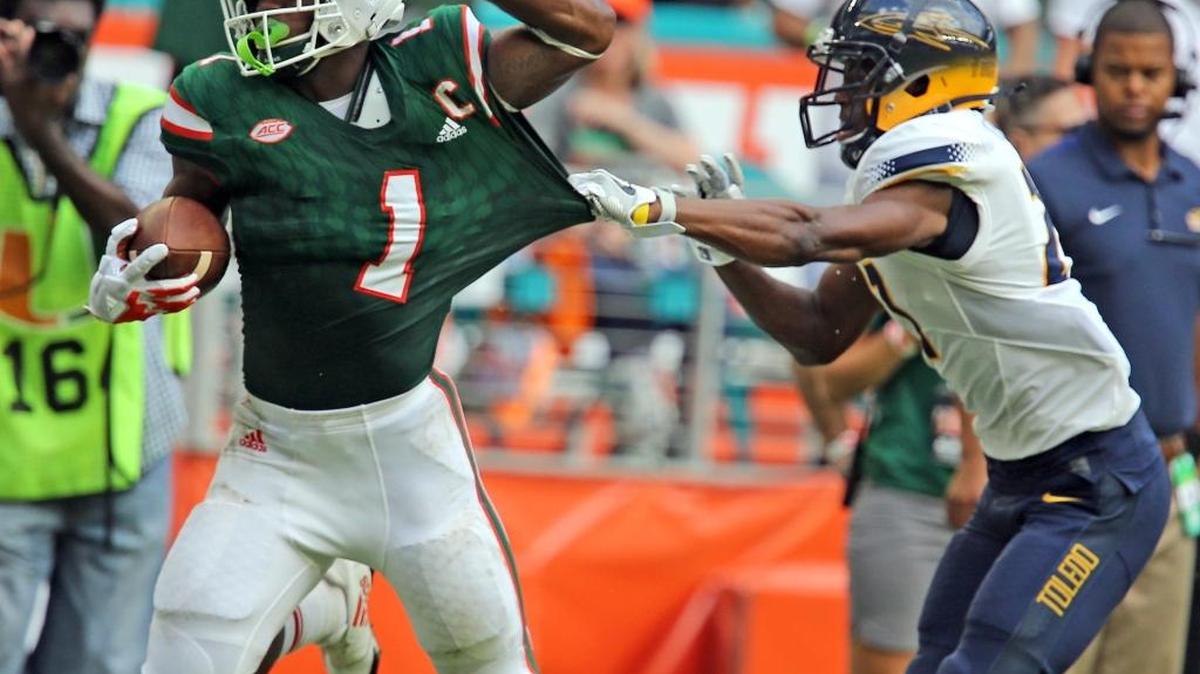 Miami Hurricanes running back Mark Walton (1) runs for a large gain as Toledo Rockets defensive back Kahill Robinson (27) stops him short of the goal in the first quarter at Hard Rock Stadium in Miami Gardens on Sept. 23, 2017.