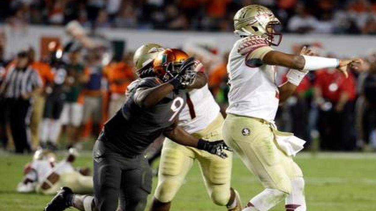 
Florida State quarterback Jameis Winston throws a pass as Miami defensive end Chad Thomas (9) and linebacker Tyriq McCord (17 defend in the second half an NCAA college football game, Saturday, Nov. 15, 2014, in Miami Gardens, Fla. Florida State defeated Miami 30-26. 
