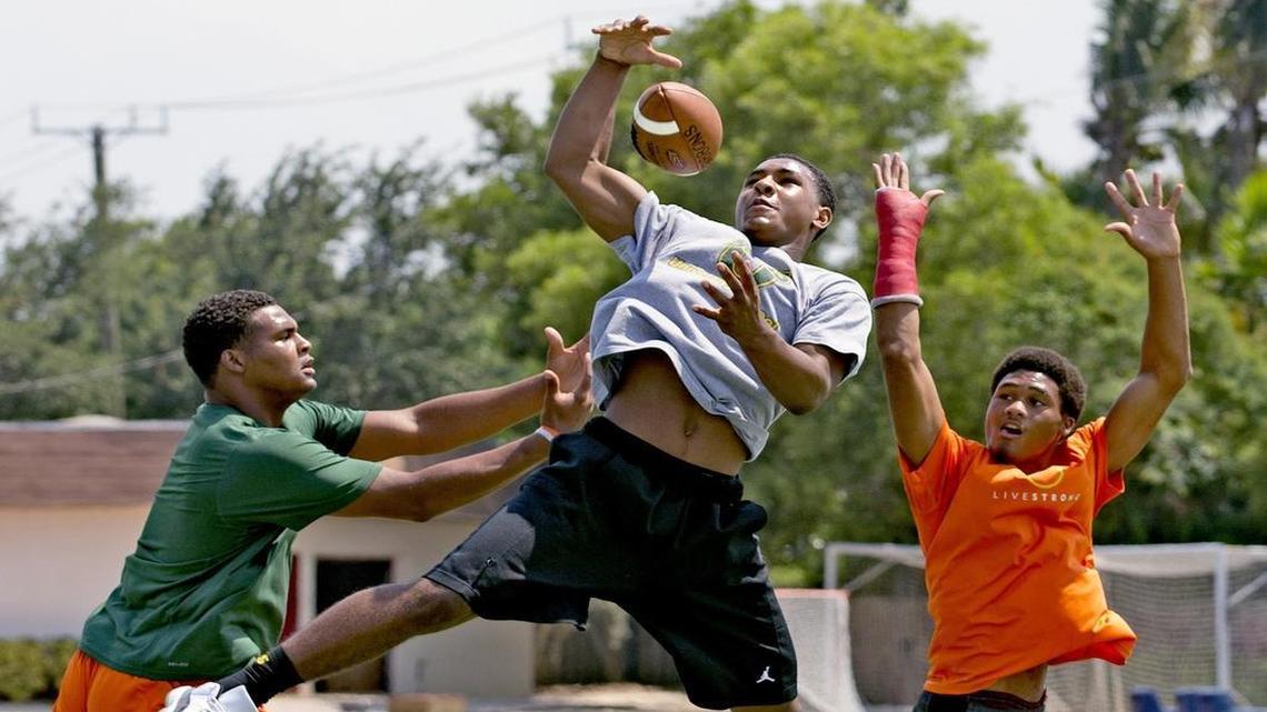 
PRIZED CATCH: Eighth grader Kenny McIntosh, center, framed by his brothers, Richard Jr., left, and Deon. Kenny is one of five eighth graders offered scholarships by UM in the past three weeks.
