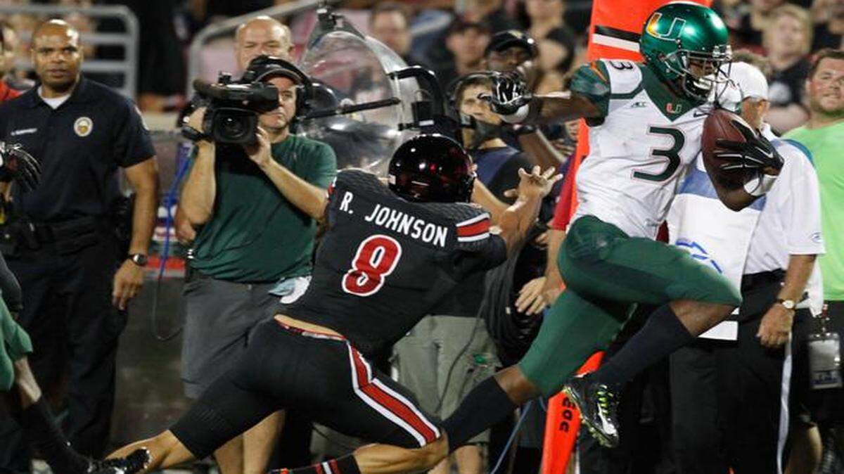 
Miami Hurricanes wide receiver Stacy Coley (3) drives past Louisville Cardinals punter Ryan Johnson (8) after a punt in the first half as the University of Miami Hurricanes play the University of Louisville Cardinals at Papa John's Cardinal Stadium in Louisville, Kentucky, on Monday, Sept. 1, 2014.
