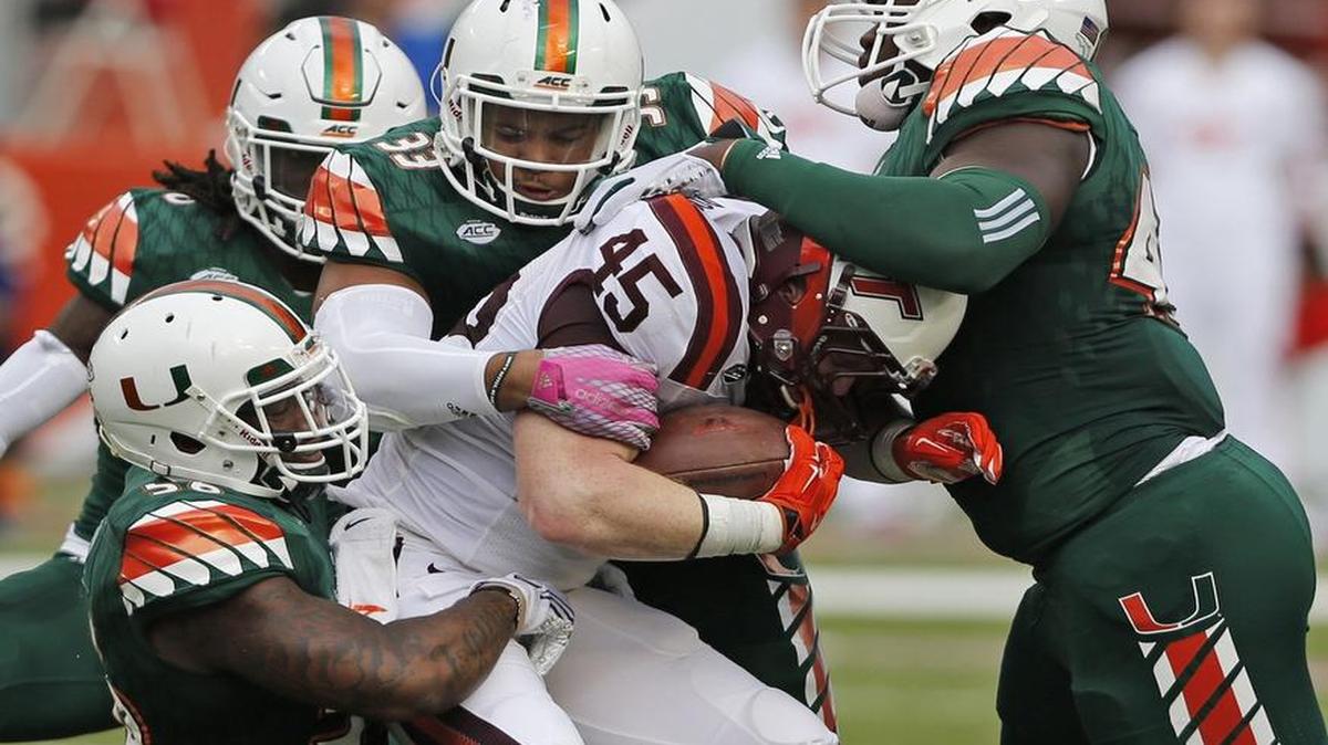 
Miami Hurricanes linebacker Raphael Kirby (56), and defensive linemen Trent Harris (33) and Ufomba Kamalu (47) gang tackle Virginia Tech Hokies fullback Sam Rogers (45) in the first quarter as the University of Miami hosts Virginia Tech at Sun Life Stadium on Saturday, October 17, 2015.
