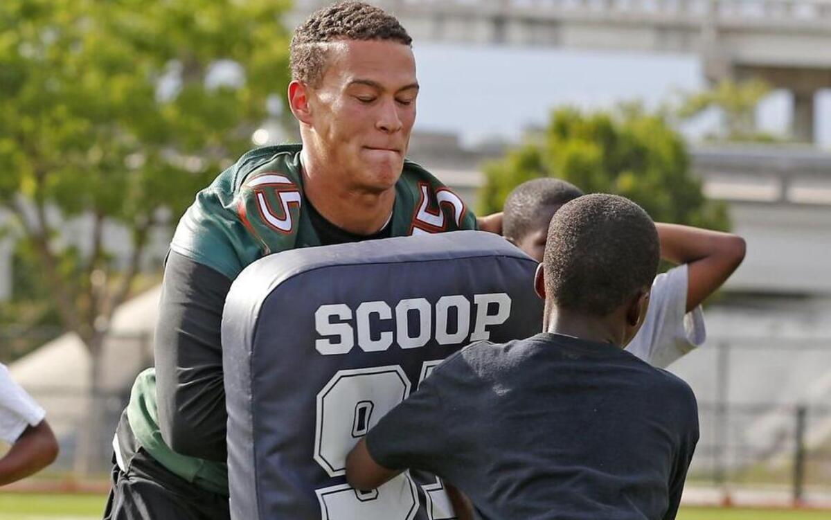 
UM quarterback Brad Kaaya runs a football drill with kids during a summer camp Wednesday, June 10, 2015 at Dade-Gibson Park in Overtown. 
