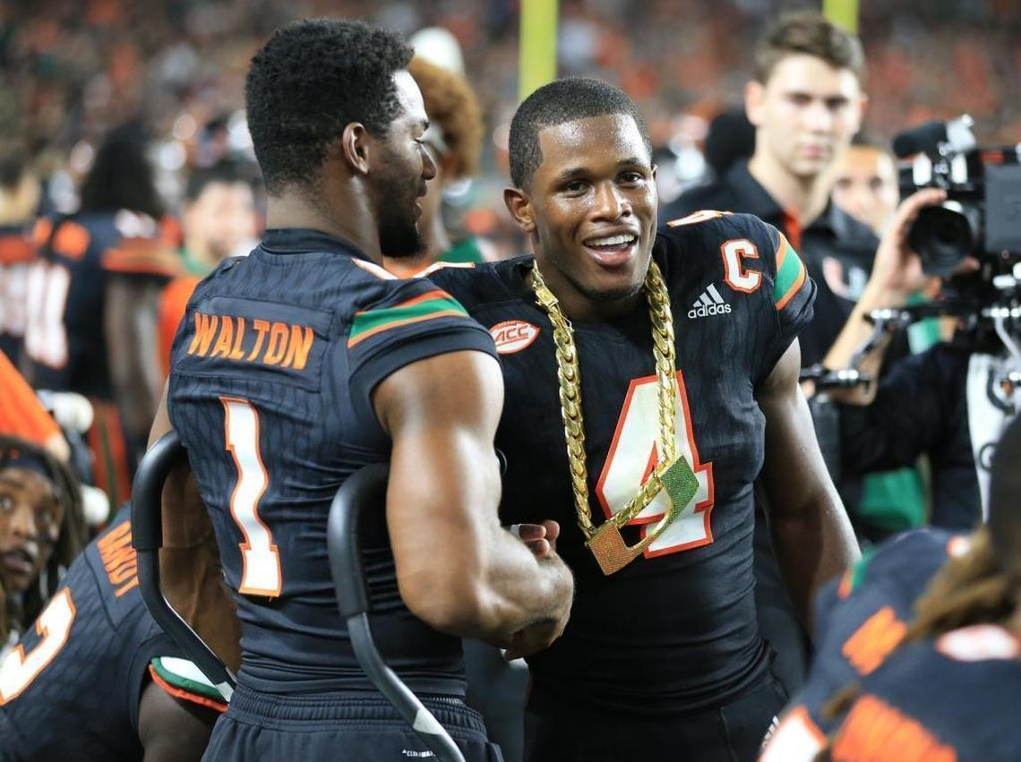 Miami Hurricanes running back Mark Walton (1) congratulates defensive back Jaquan Johnson (4) after receiving the turn over chain as the University of Miami hosts Virginia Tech Hokies at Hard Rock Stadium on Sat., Nov. 4, 2017.