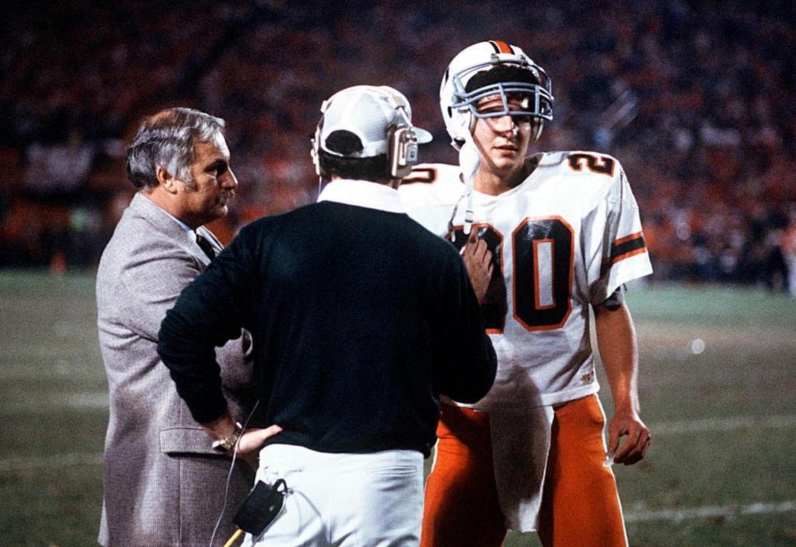 Miami quarterback Bernie Kosar confers with coach Howard Schnellenberger and offensive coordinator Gary Stevens in the 1984 Orange Bowl, when UM won its first national title.