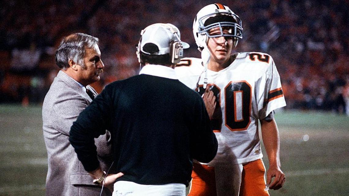 Miami quarterback Bernie Kosar confers with coach Howard Schnellenberger and offensive coordinator Gary Stevens in the 1984 Orange Bowl, when UM won its first national title. Kosar spoke to UM players last Friday night in Toledo.
