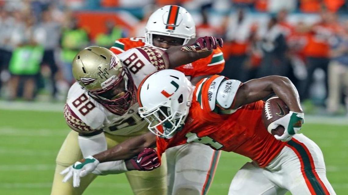 Miami Hurricanes' Jaquan Johnson intercepts the ball in the second quarter to help set up a touchdown as Florida State Seminoles' Marvin Saunders tackles him at Hard Rock Stadium in Miami Gardens.