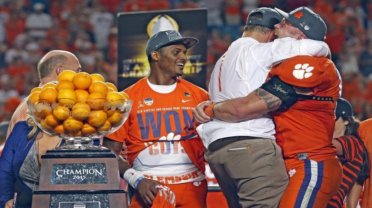 Clemson Tigers quarterback and Offensive MVP Deshaun Watson watches as coach Dabo Swinney and Defensive MVP Ben Boulware hug while celebrating after defeating the Oklahoma Sooners in the 2015 College Football Playoff Semifinal at the Capital One Orange Bowl at SunLife Stadium in Miami Gardens, Florida, Dec. 31, 2015.