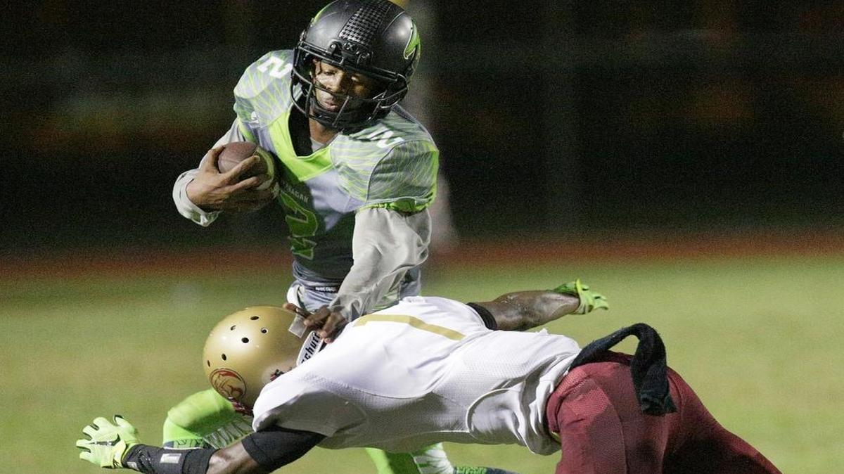 Flanagan Stanford Samuels (2) pushes away Coconut Creek defender while carrying the ball during their football game on Friday, September 4, 2015 at Flanagan High School in Pembroke Pines.
