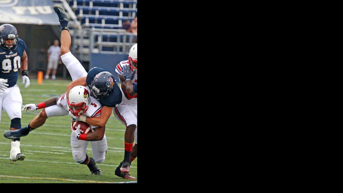 
FIU's Justin Hailey tackles Louisville's Michael Dyer as he advances the ball to help set up Louisville's first-quarter touchdown at Ocean Bank Field at FIU Stadium in Miami on Satuday, Sept. 20, 2014.
