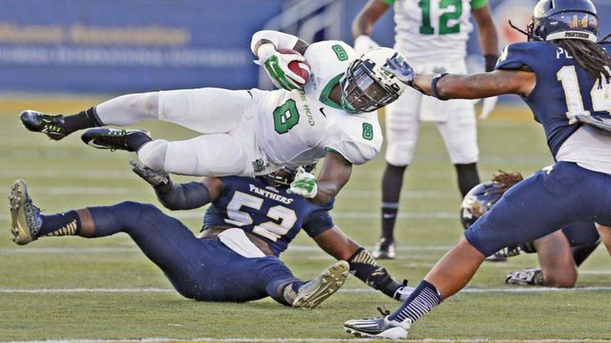 
Marshall Thundering Herd running back Remi Watson (8) is taken off his feet by FIU Panthers linebacker Treyvon Williams (52) in the first quarter as Florida International University hosts Marshall at Ocean Bank Stadium in Miami on Saturday, October 18, 2014.
